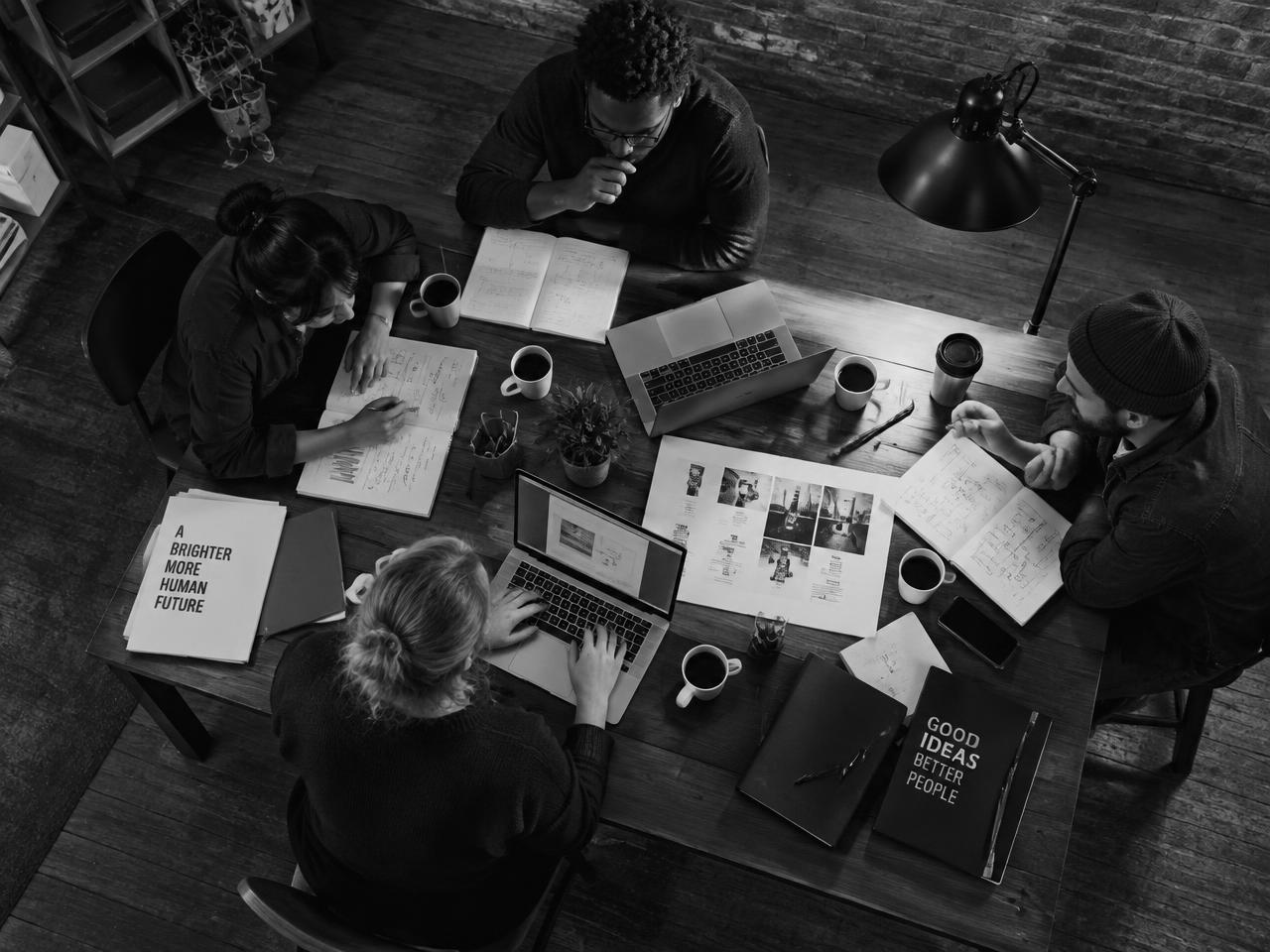 Team collaborating around a table of laptops and notes